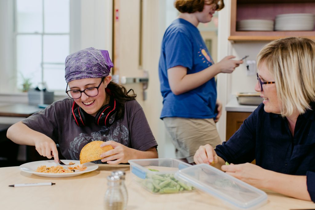 three people sitting in front of table laughing together