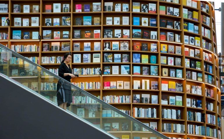 Woman on escalator with library behind her