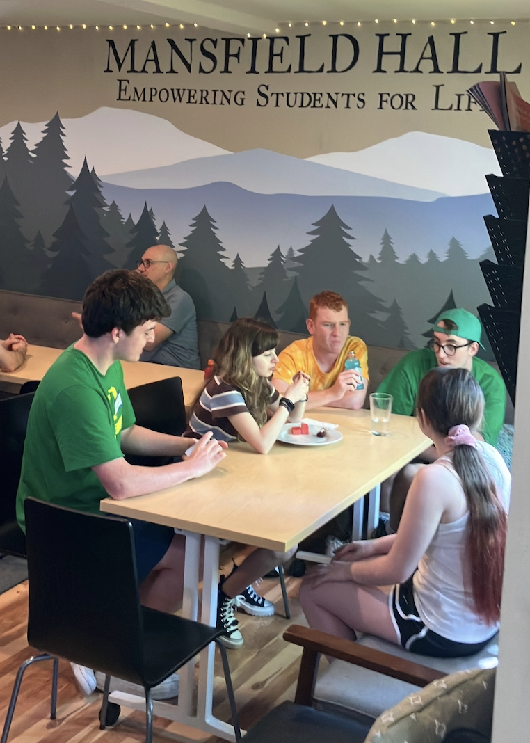 three people sitting in front of table laughing together